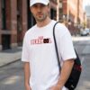 White Oversized Graphic T-Shirt with Front Typography Print and Back Comic Artwork Design Paired with Matching Adjustable Cap and Drawstring Bag Combo Set Streetwear Casual Everyday Outfit